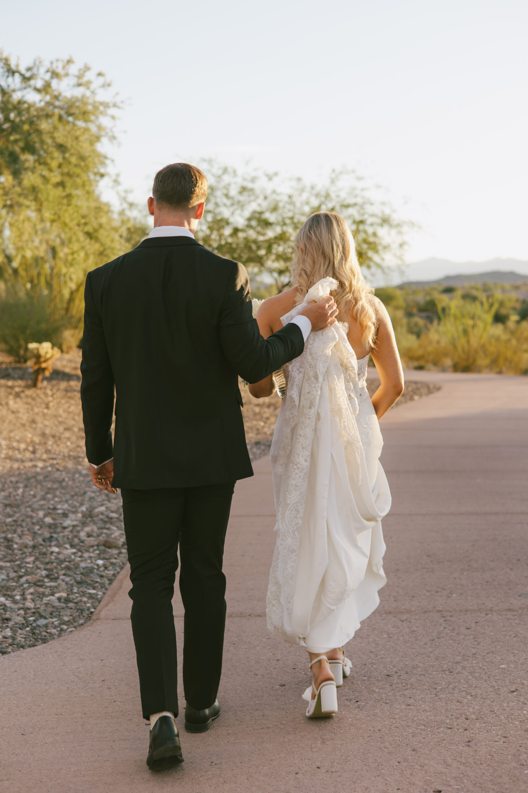 Gentleman Groom Matt holding his bride Alexa's dress Professional wedding photographer in Arizona