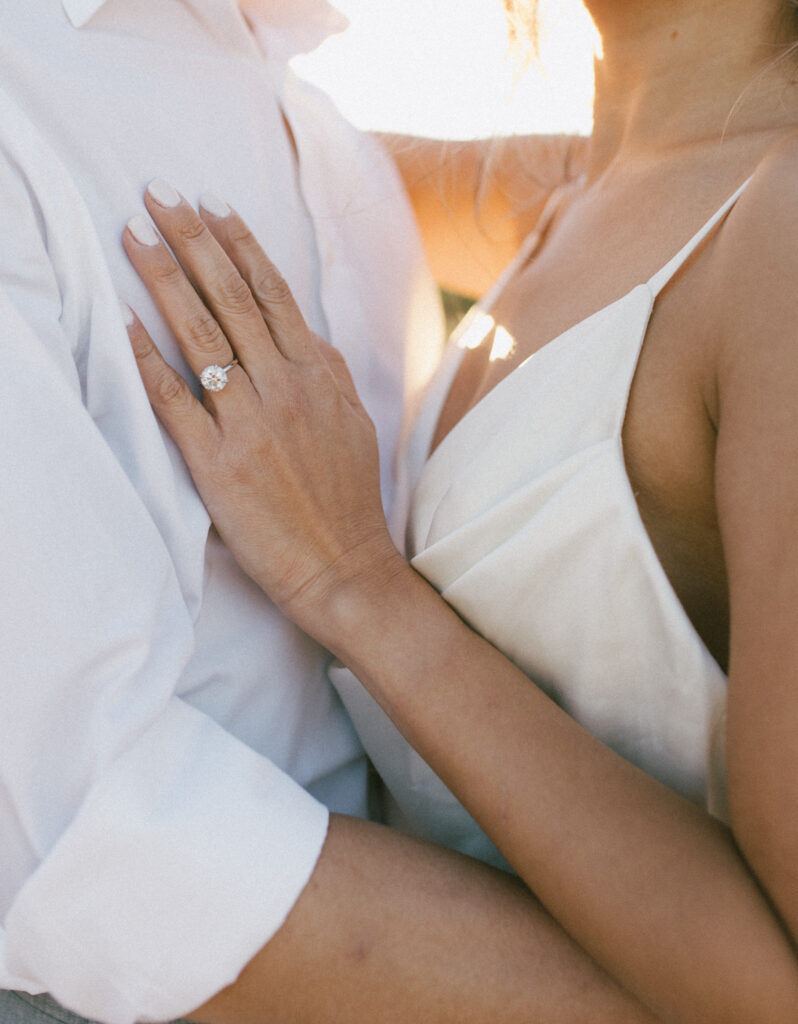 Close up shot of J and Alice embracing capturing a close up of her ring during their Arizona Sunrise Engagement Session