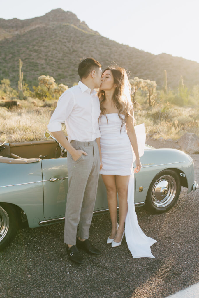 J and Alice's Blue Classic Car Arizona Engagement Session. J & A standing outside of the blue classic car sharing a gentle kiss