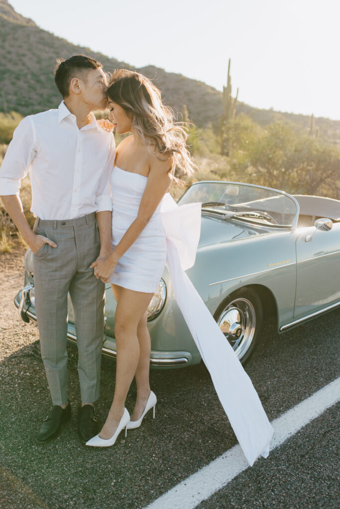 Arizona wedding photographer Jaidyn Michele captures an intimate embrace and soft forehead kiss of J and Alice during their sunrise Arizona Engagement Session in front of the classic car