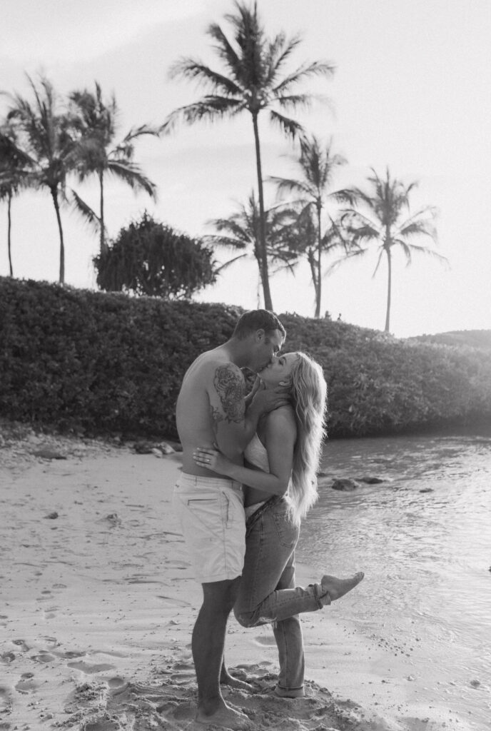 Gabby and Kyle at Oahu sunset in their swim suits sharing a kiss Black and White image, Oceanfront Engagement Session, Beach Engagement Session, Hawaii Engagement Photographer
