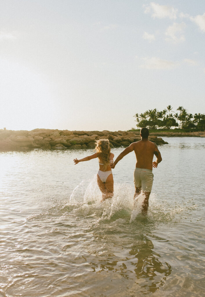 Gabby and Kyle run into the ocean during their Oahu Engagement Session