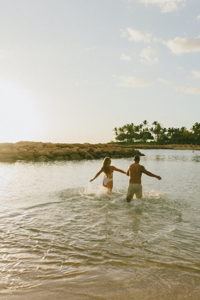 Oahu Engagement Session Gabby and Kyle run in the ocean during sunset
