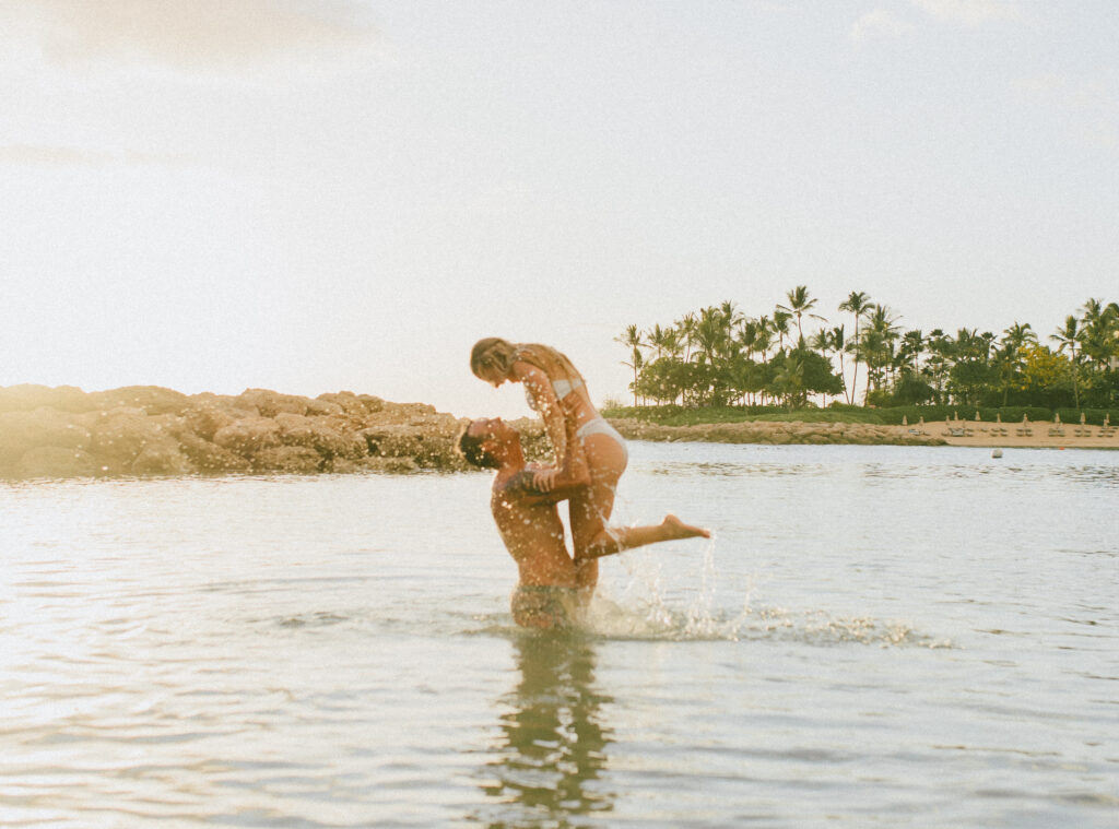 Sunset Oahu Engagement Session Kyle lifting Gabby out of the water, Beach Engagement Session, Hawaii Engagement Photographer, Destination Engagement Photographer