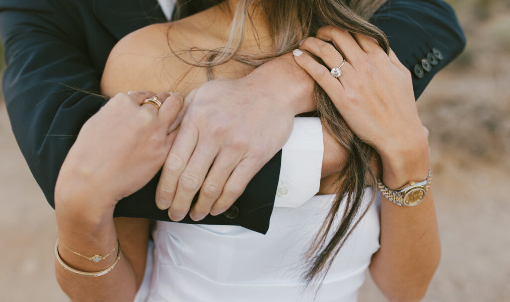 Close up shot of J and Alice embracing capturing a close up of her ring during their Arizona Sunrise Engagement Session formal attire