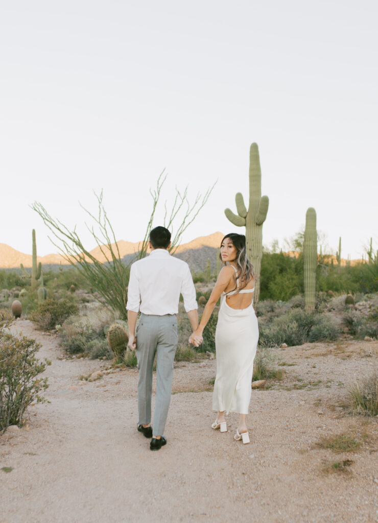 J and Alice’s Arizona Engagement Session walking hand in hand in the desert casual attire