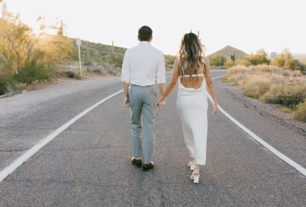 J and Alice’s Arizona Engagement Session walking hand in hand down the street away from camera