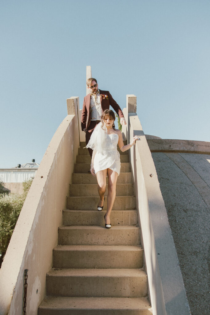 Bride and groom walking downstairs posing for photos at Arcosanti in the Arizona desert. 