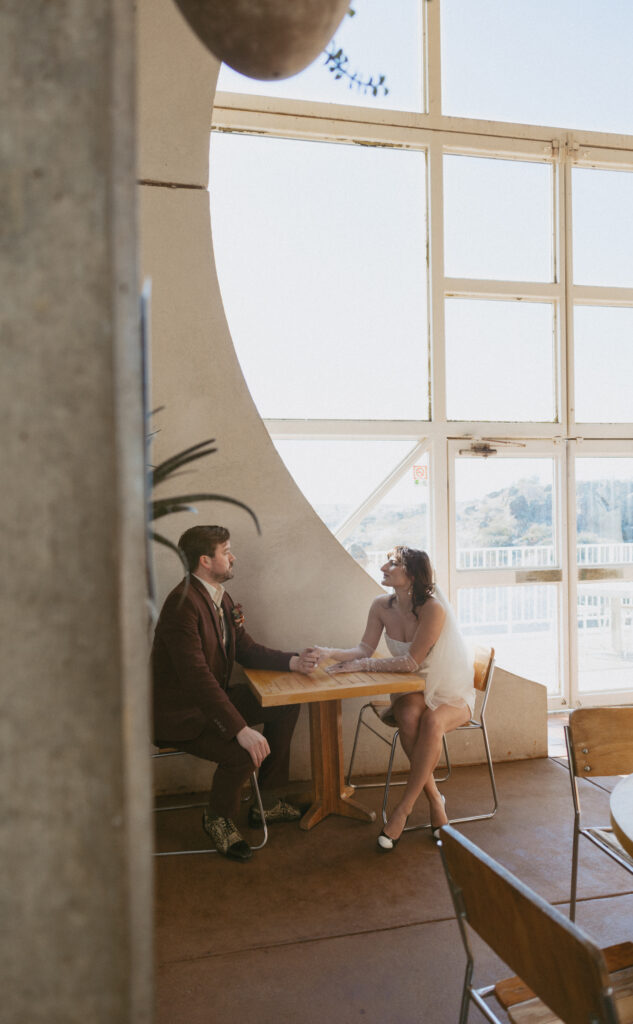 Bride and groom on their elopement day sitting in the cafe at Arcosanti. 