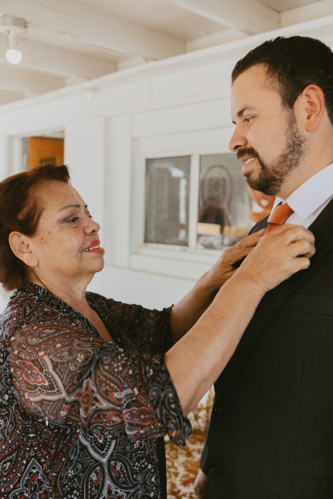 Groom getting ready with his mom at a AirBnb on his wedding day.