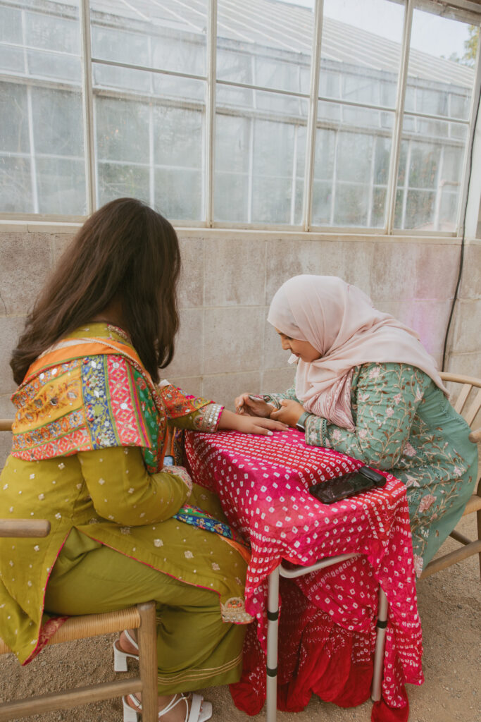 Henna artist tattooing at wedding reception.