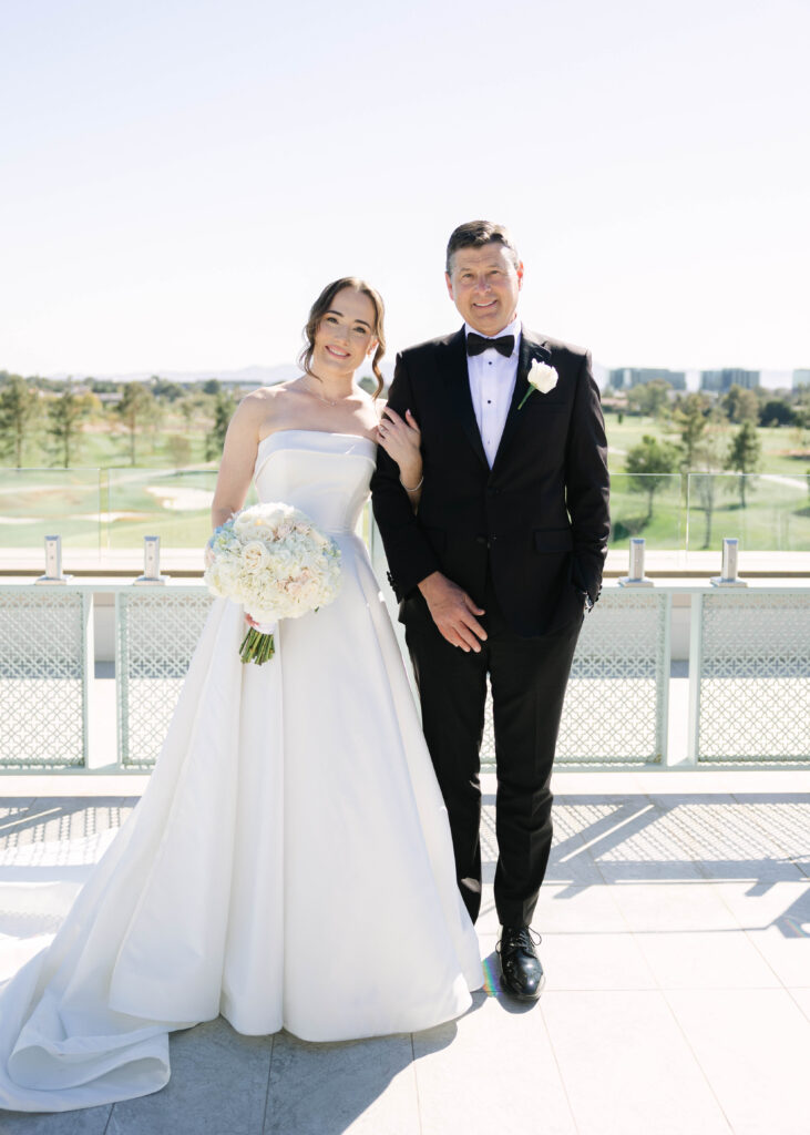 Bride and Father of the Bride stand posing on a rooftop terrace at Arizona Biltmore Golf Club after they exchange a first look on Bride's wedding day.