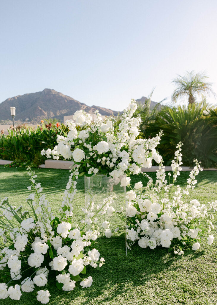 A beautiful outdoor wedding at the Camelback Inn, featuring expansive lawns and sweeping mountain views, with stunning white ceremony florals.