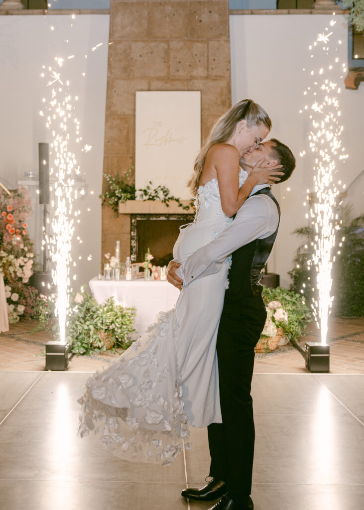 Bride and groom sharing their first dance at the wedding reception, with dazzling cold sparks lighting up the background for a magical moment.